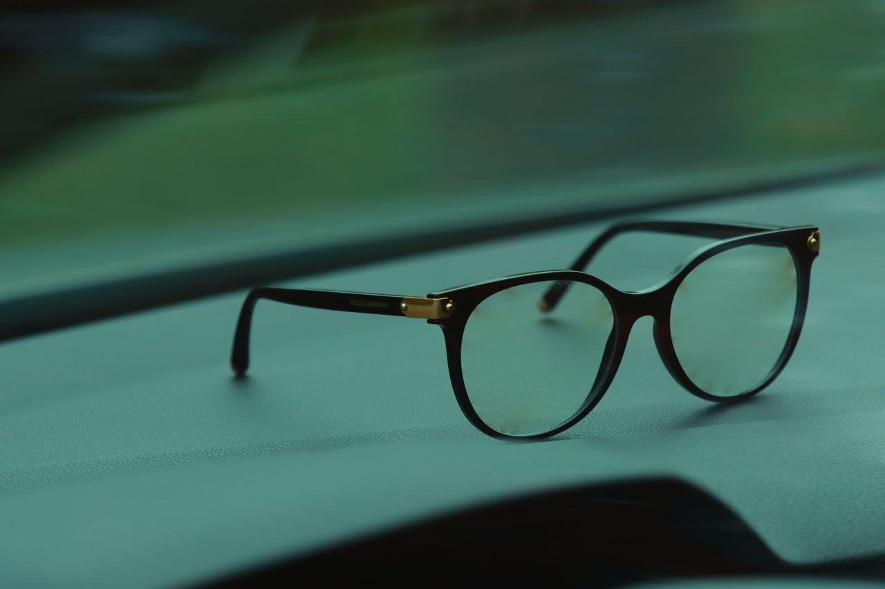 Close-up of stylish black eyeglasses resting on a car dashboard. Perfect for eyewear and fashion themes.